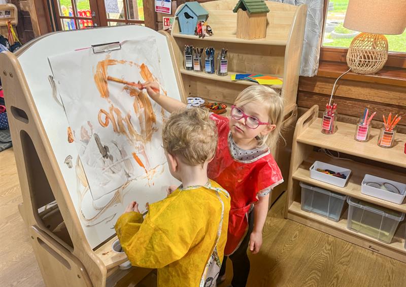 Two children are painting on an art easel that has been supplied by Millhouse